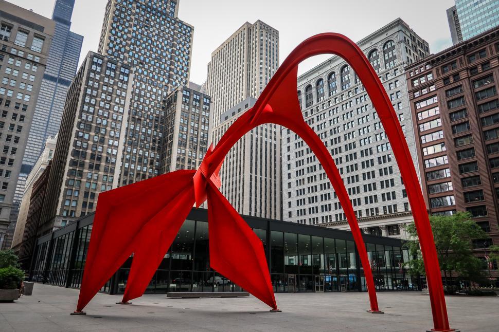 Free Image of Modern buildings surround the iconic Flamingo sculpture artwork 