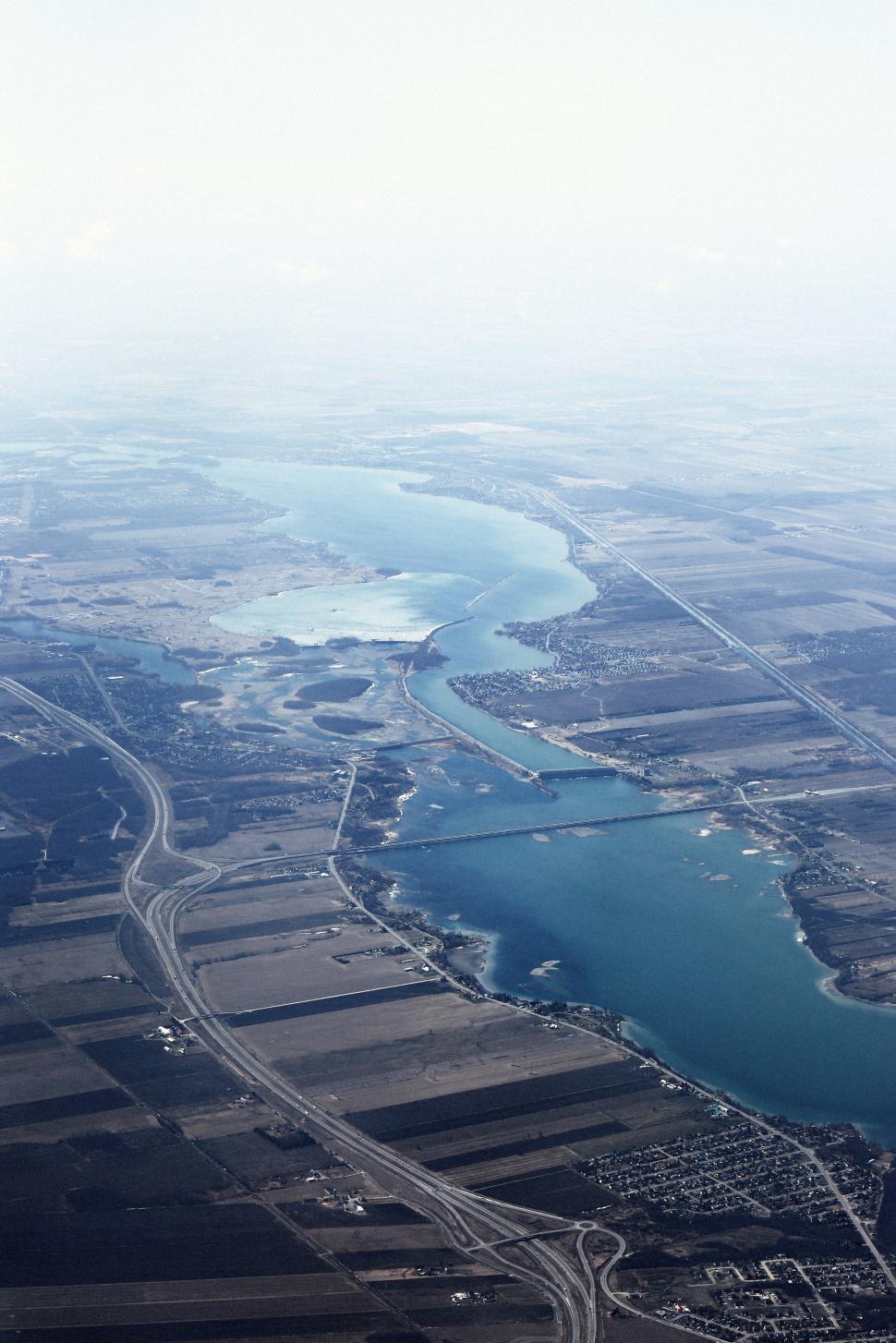 Free Image of Aerial view of winding river passing through farmland and bridges. 
