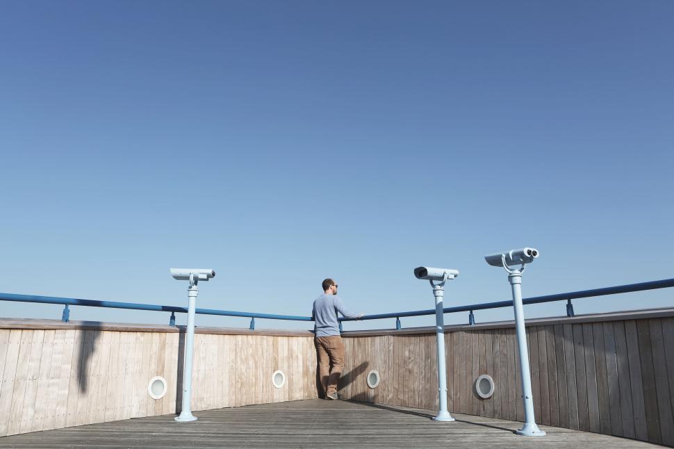 Free Image of Person looking through telescopes on seaside observation deck 