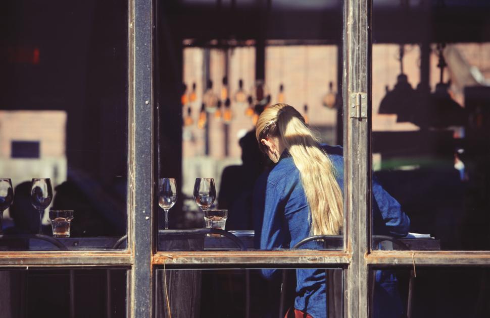 Free Image of Customer at cafe with glass wall, reflecting urban city life. 