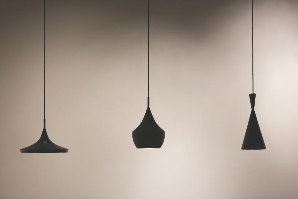 Free Image of Set of three modern black pendant lights in a minimalist setting. 