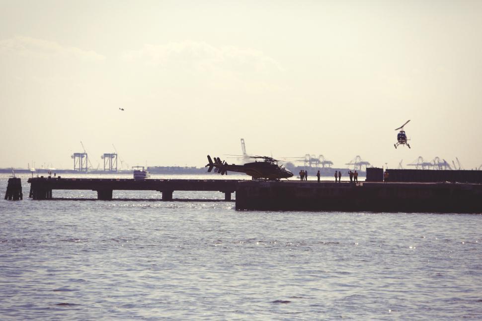 Free Image of Helicopters landing on a pier with industrial background skyline. 