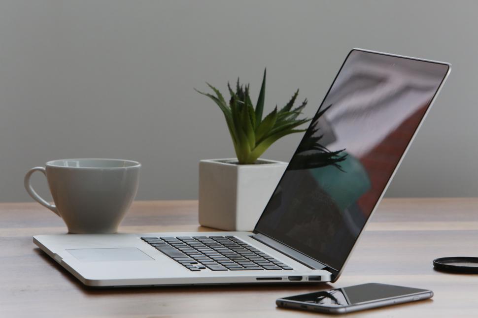 Free Image of Modern workspace with laptop, coffee, and plant on wooden desk 