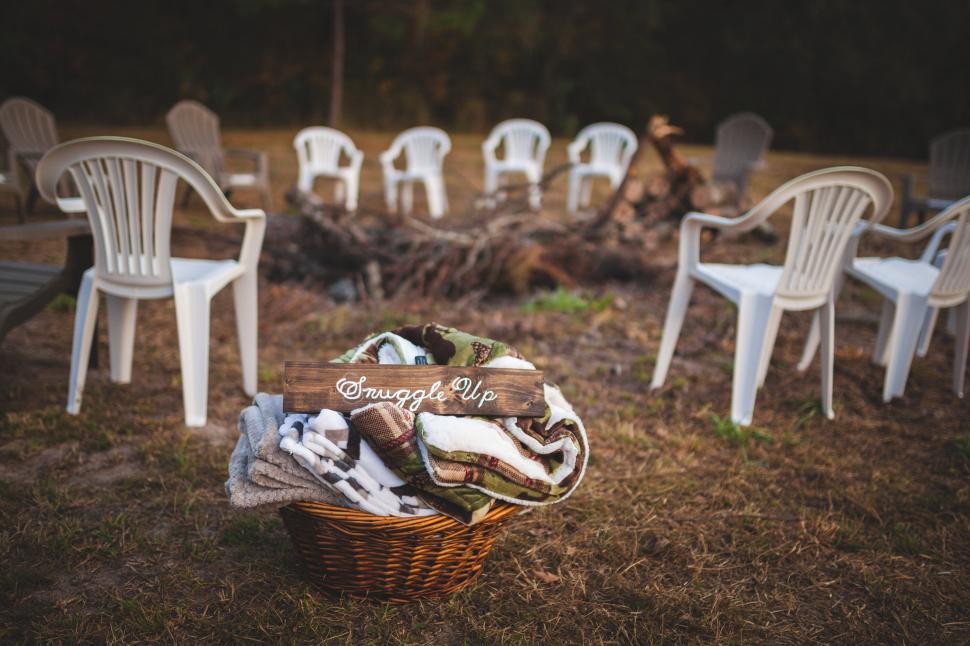 Free Image of Basket of cozy blankets near a circle of chairs ready for gathering. 