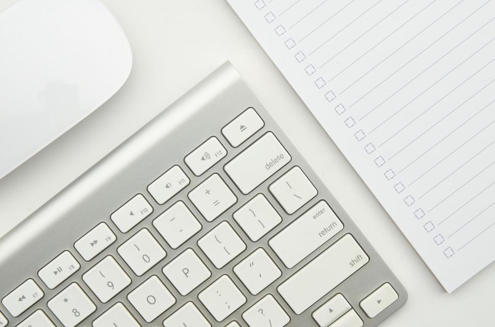 Free Image of Silver keyboard and notepad with checkbox lines on white surface 