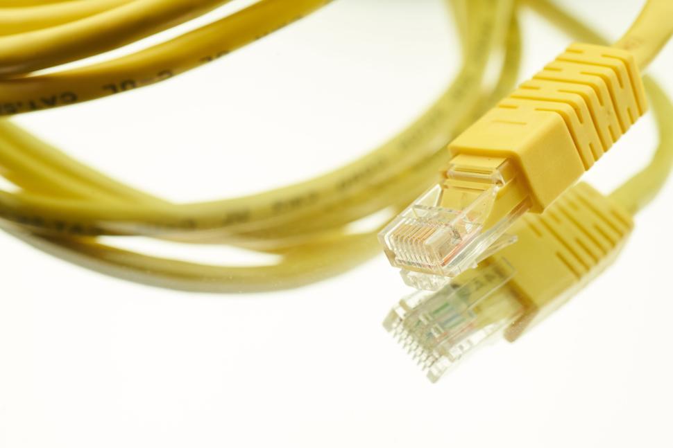 Free Image of Yellow Ethernet cable and plug reflecting on white background 