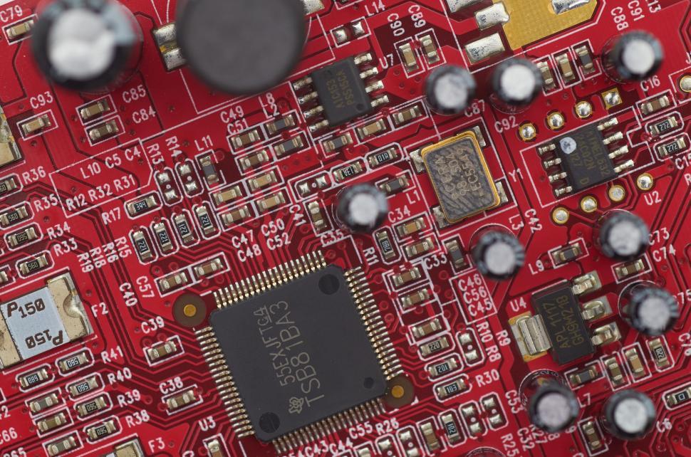 Free Image of Detailed view of a red printed circuit board with various components 