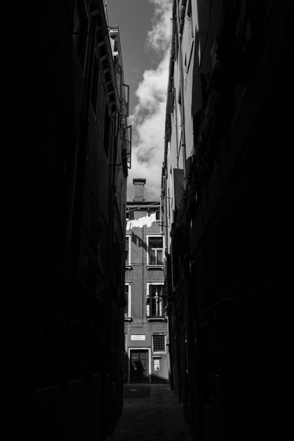Free Image of Narrow alleyway in European city with sunlight hitting the end. 