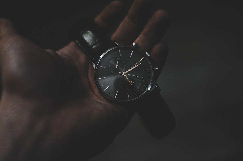 Free Image of Hand holding a classic wristwatch in a dimly lit, vintage-style setting. 