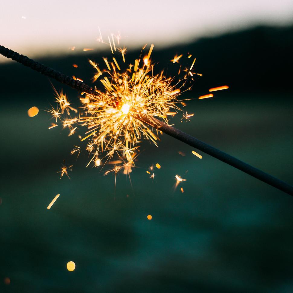 Free Image of Sparkler emitting bright sparks against a blurred dark background 
