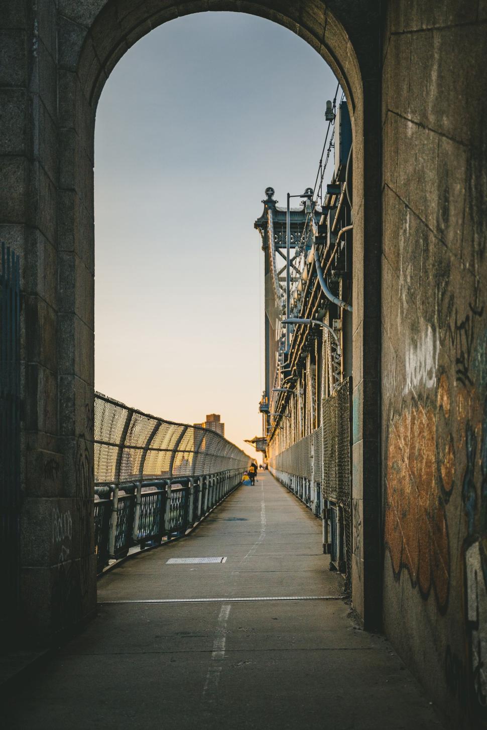 Free Image of Bridge walkway with sunset view through archway, serene moment 
