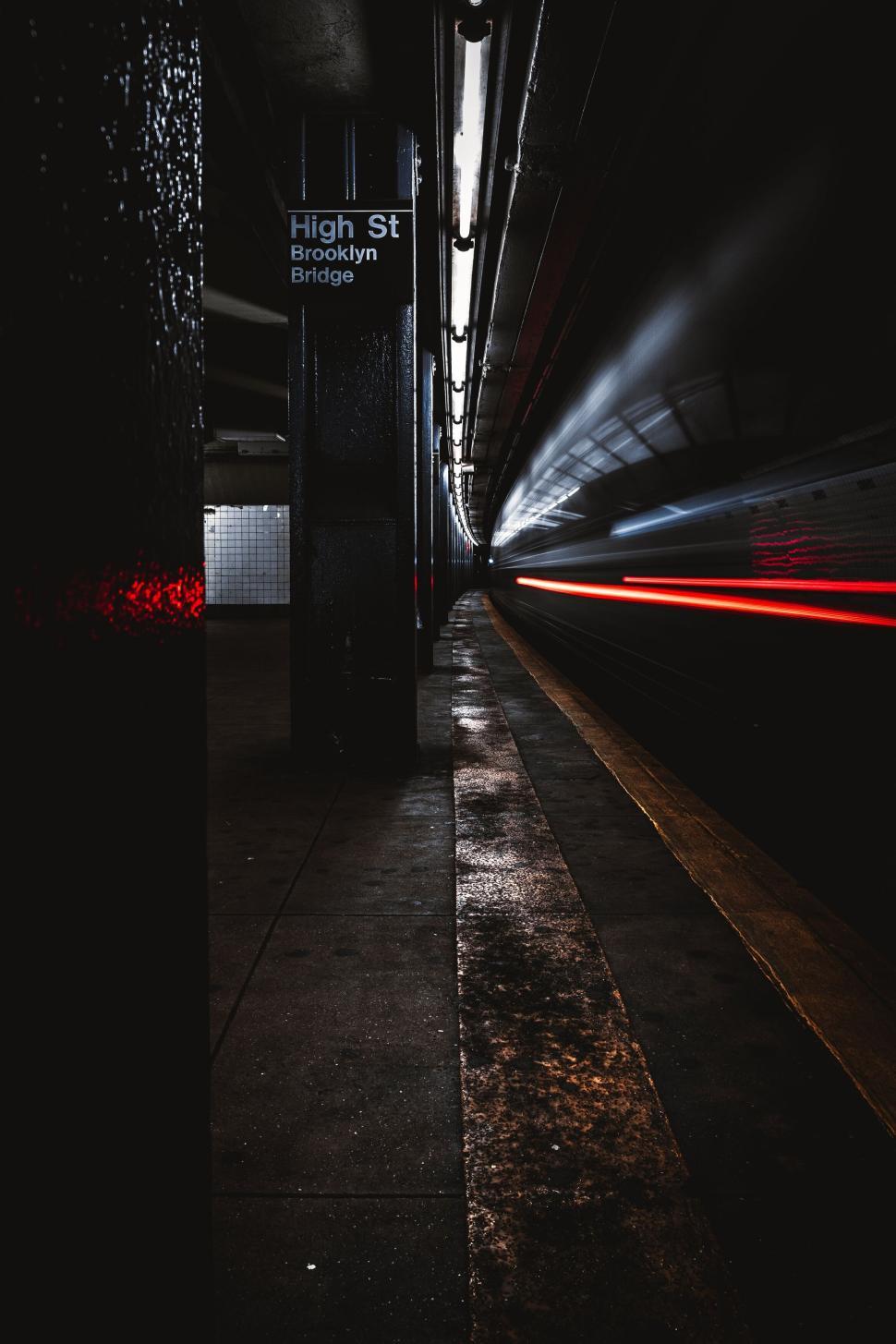 Free Image of Subway station platform at nighttime with light trails from train. 