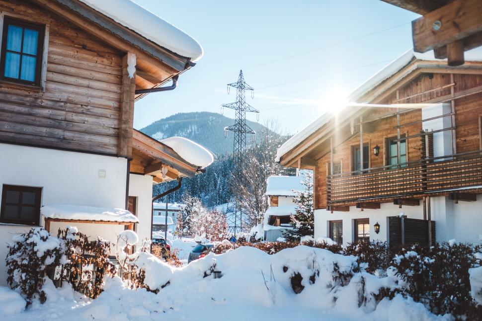 Free Image of Snow-covered wooden houses in a mountain village at sunrise. 