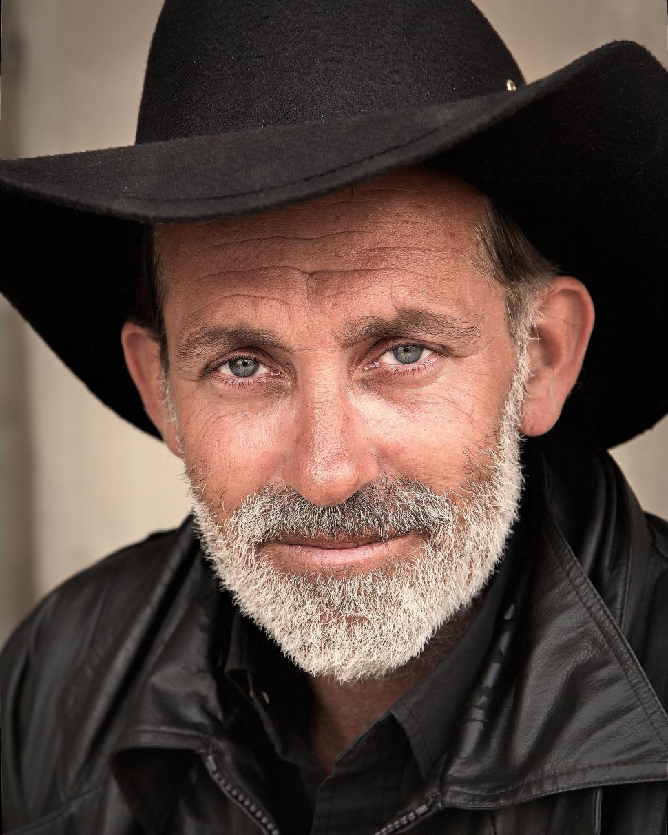 Free Image of Old man in black cowboy hat and leather jacket, facing camera. 