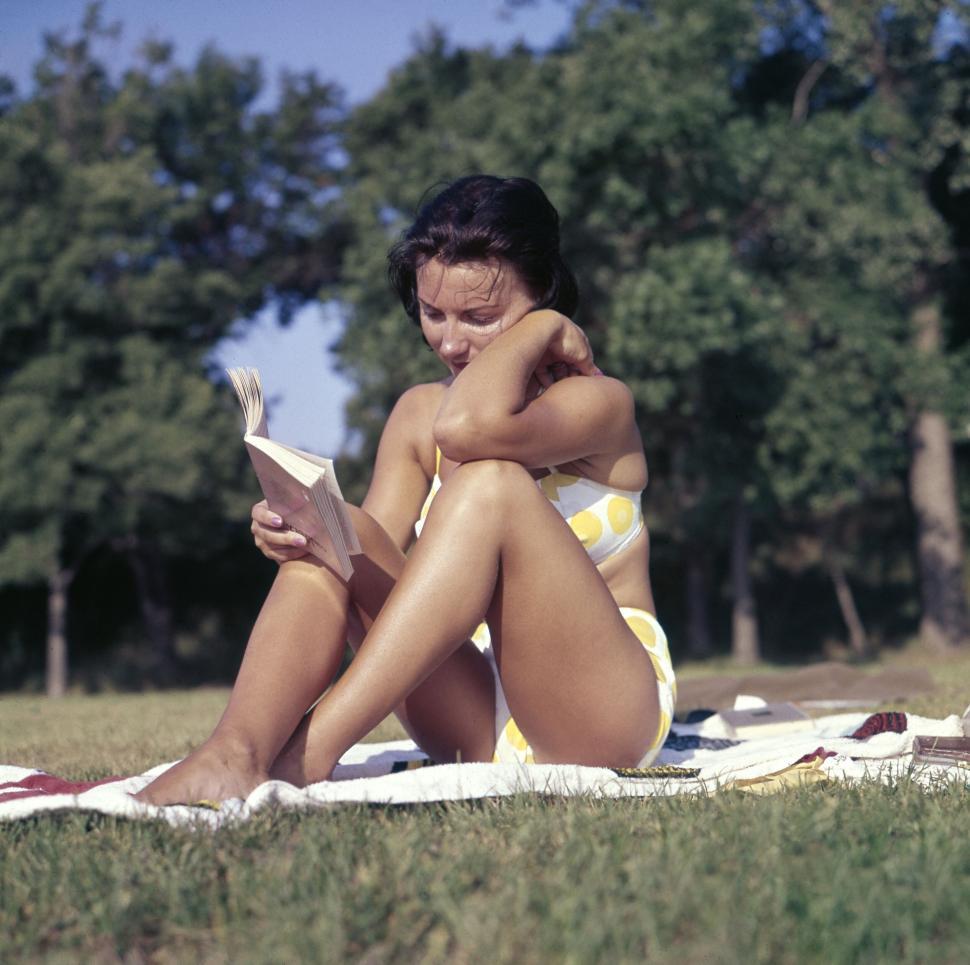 Free Image of Person in yellow polka-dot bikini reading book on grass outdoors. 