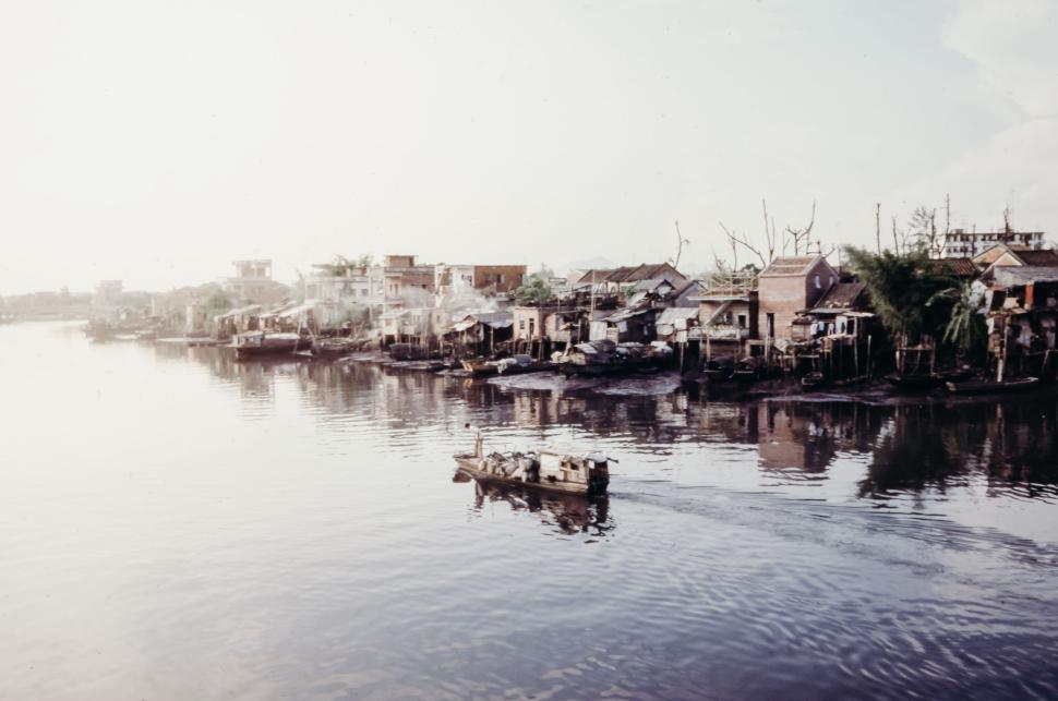 Free Image of Serene village by river with boats and rustic houses 
