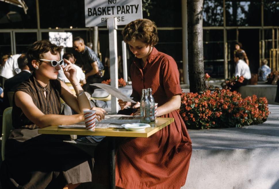 Free Image of Two women sitting at outdoor caf? table reading menus, chatting. 