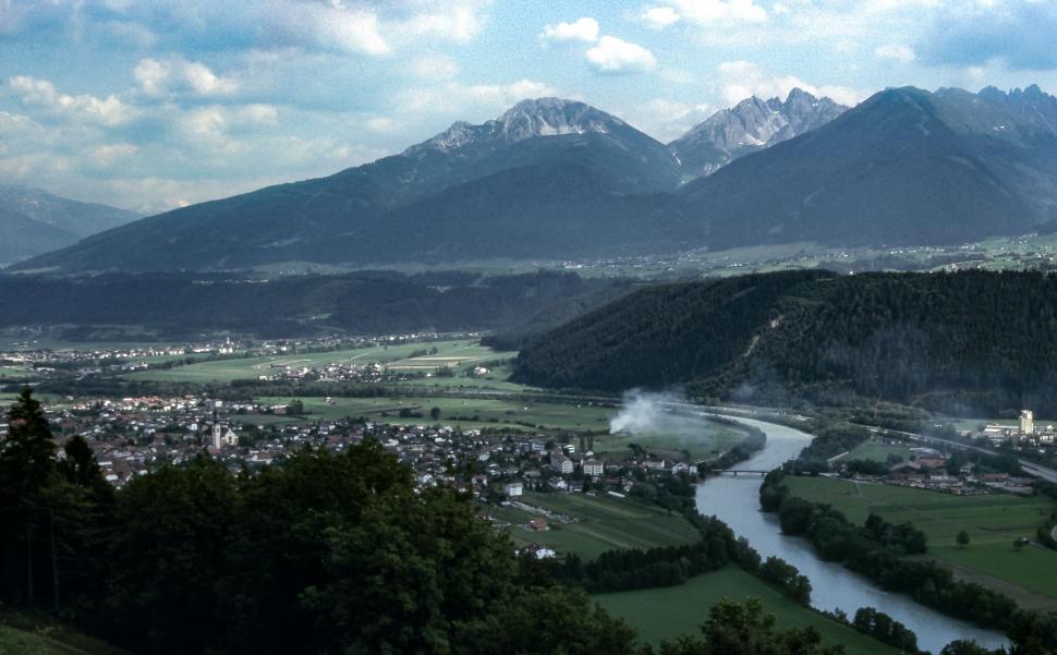 Free Image of Scenic mountain valley with river and town under blue cloudy sky. 