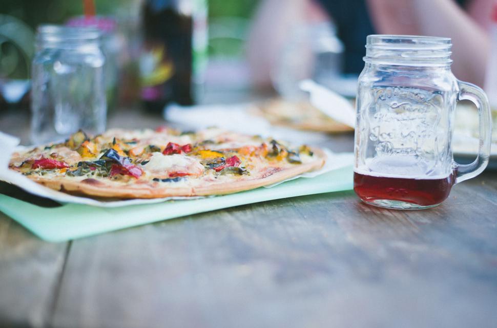 Free Image of Outdoor dining table set with pizza and mason jar drinks. 