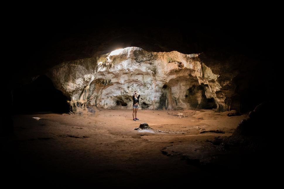 Free Image of Person stands in the middle of a large cave with natural light 