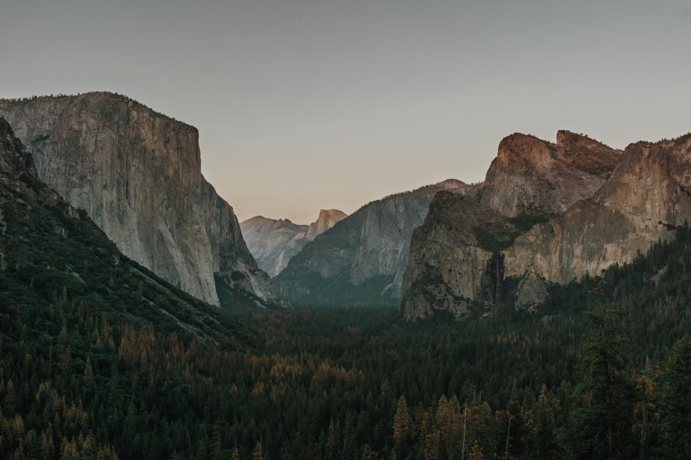 Free Image of Sweeping view of vast valley surrounded by high rocky mountains. 