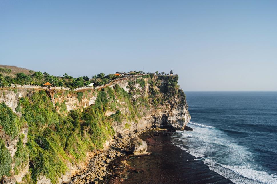 Free Image of Dramatic coastal cliffside with waves crashing along the shore 
