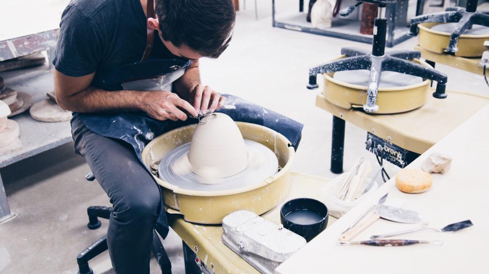 Free Image of Person working on a pottery wheel shaping a ceramic bowl carefully 