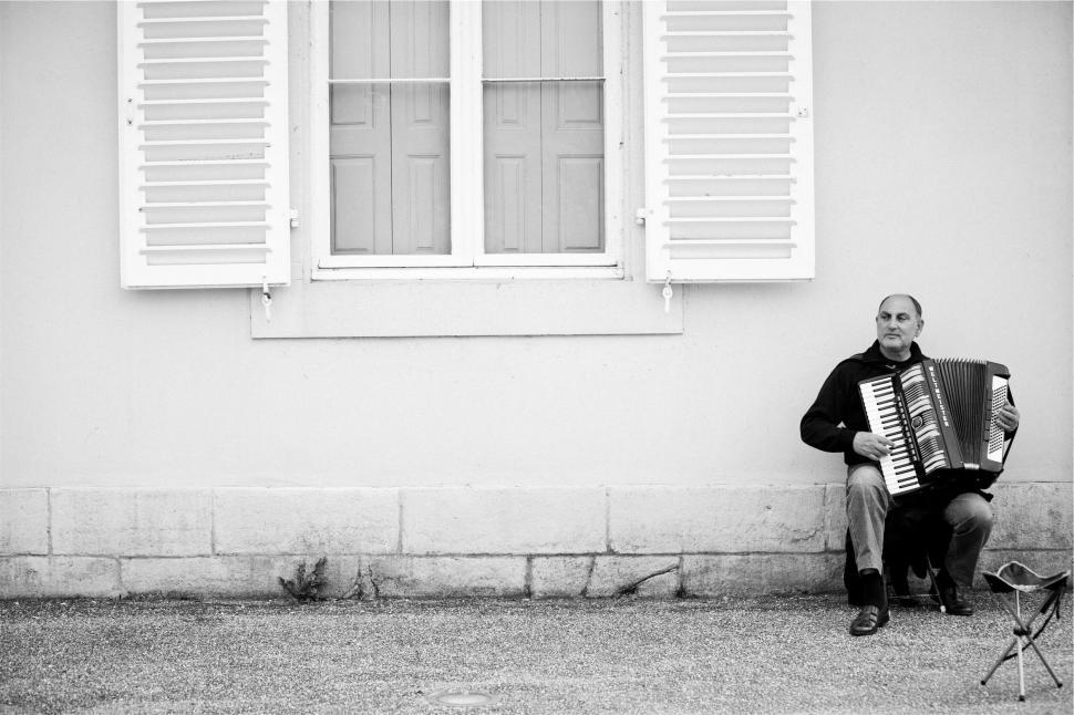 Free Image of Street musician playing accordion outside in an urban setting 