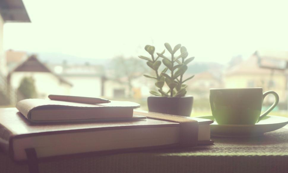 Free Image of Cup of coffee with journal and pen staged on outdoor patio. 