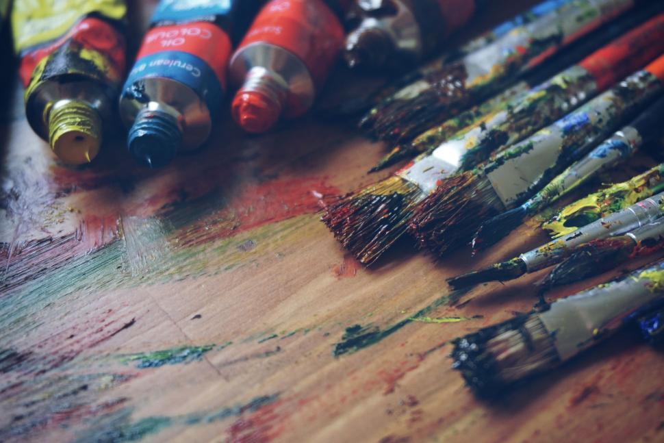 Free Image of Colorful paint tubes and brushes scattered across messy artist table. 