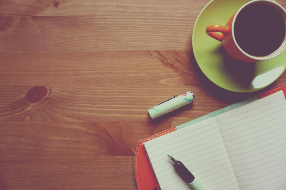 Free Image of Notebook and pen alongside coffee cup on wooden desk setup. 