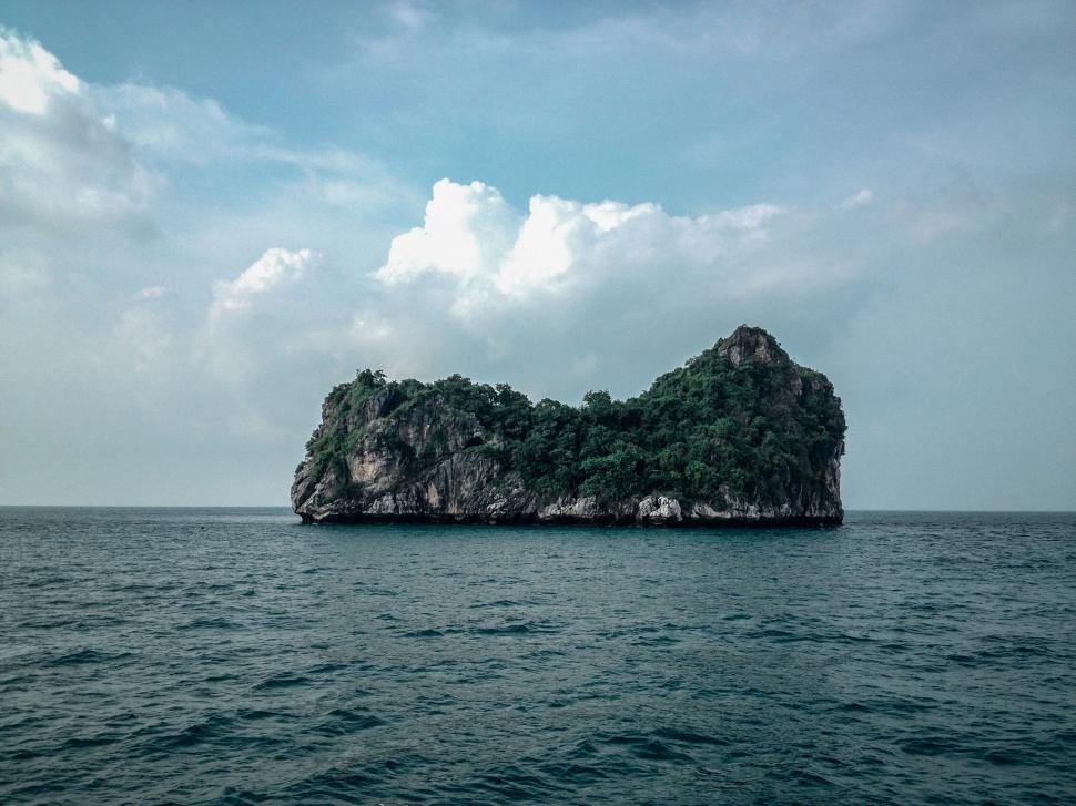 Free Image of Lonely island in the sea with lush green vegetation and cloudy sky 