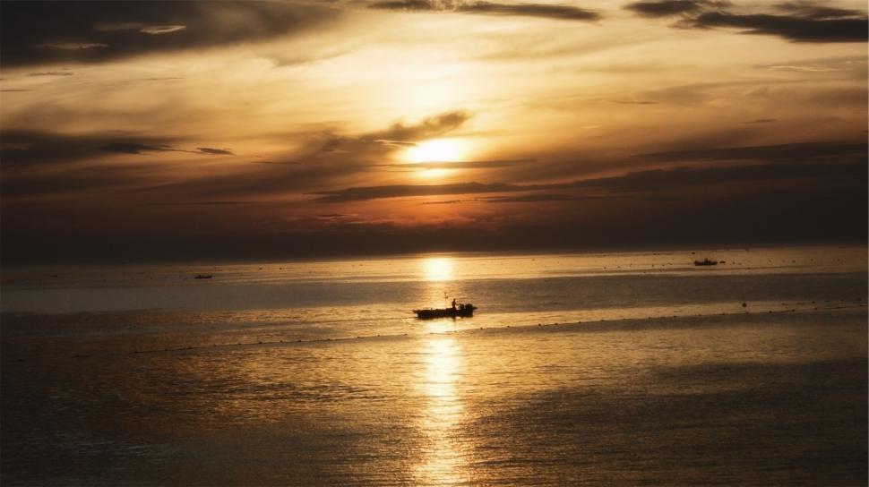 Free Image of Boat sailing in a calm sea during golden sunset, serene atmosphere 