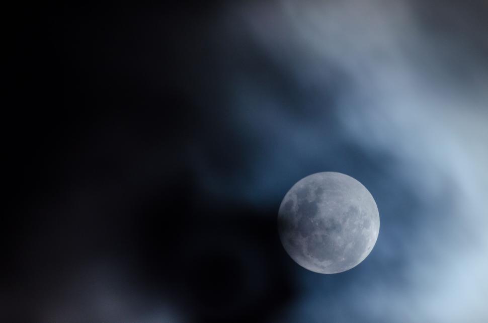 Free Image of Close-up view of the full moon surrounded by clouds at night 