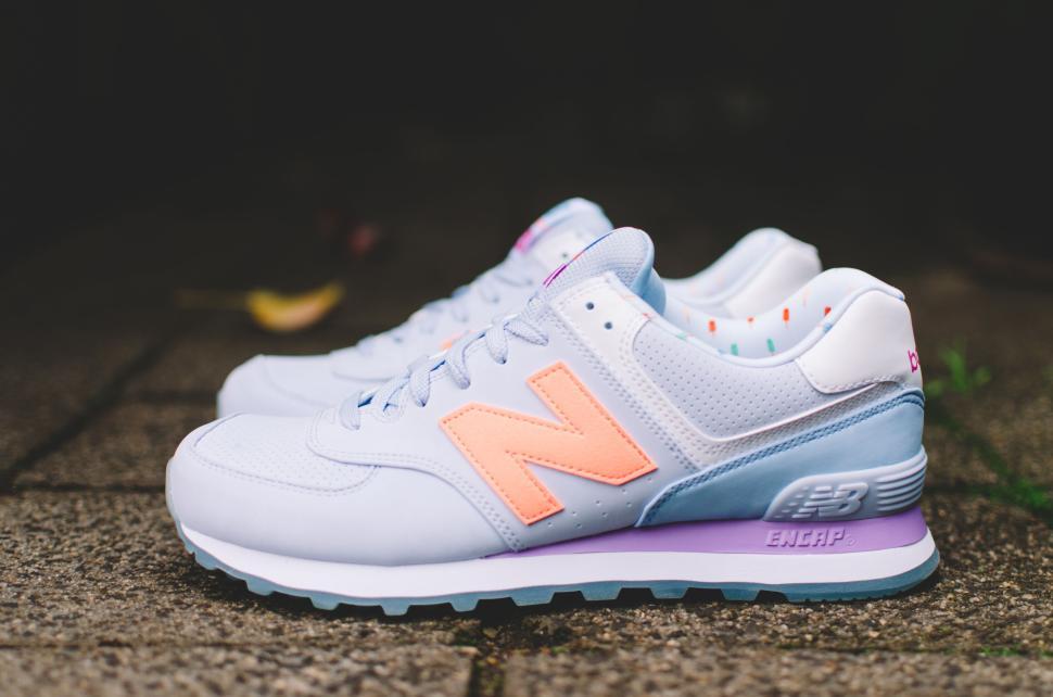 Free Image of Pair of stylish New Balance sneakers on pavement with soft focus. 