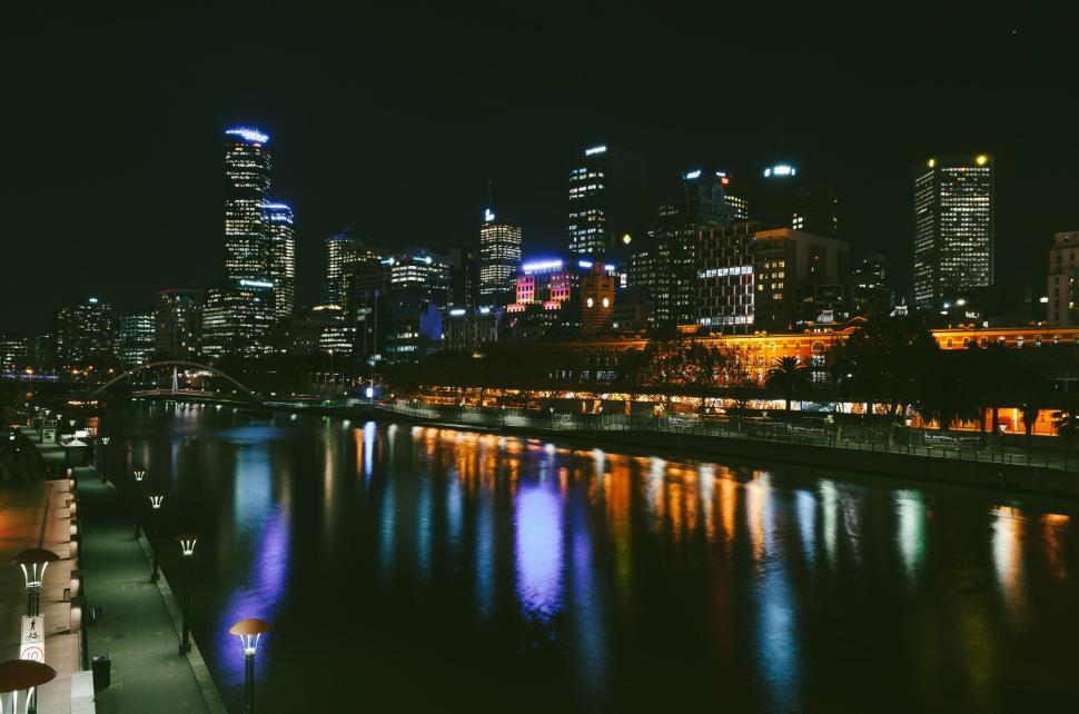 Free Image of Night view of cityscape with illuminated buildings by river waterfront 