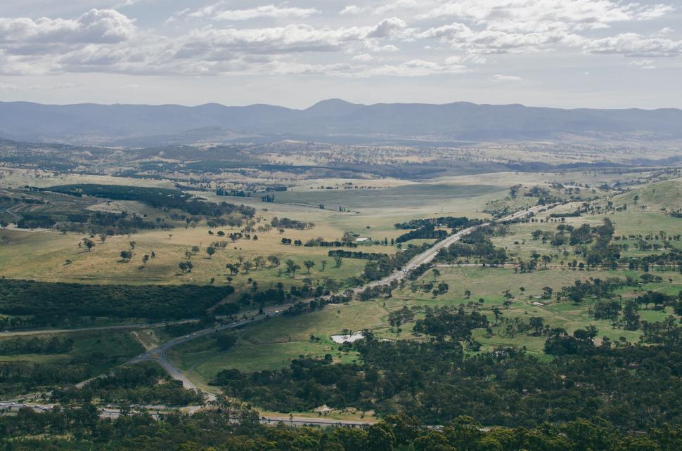 Free Image of Expansive aerial view of countryside with fields, roads, and mountains 