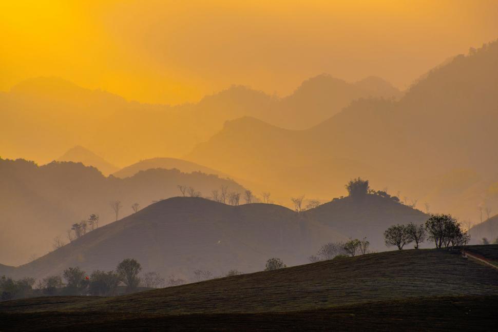 Free Image of Mountainous landscape at sunset with layered peaks and orange sky 
