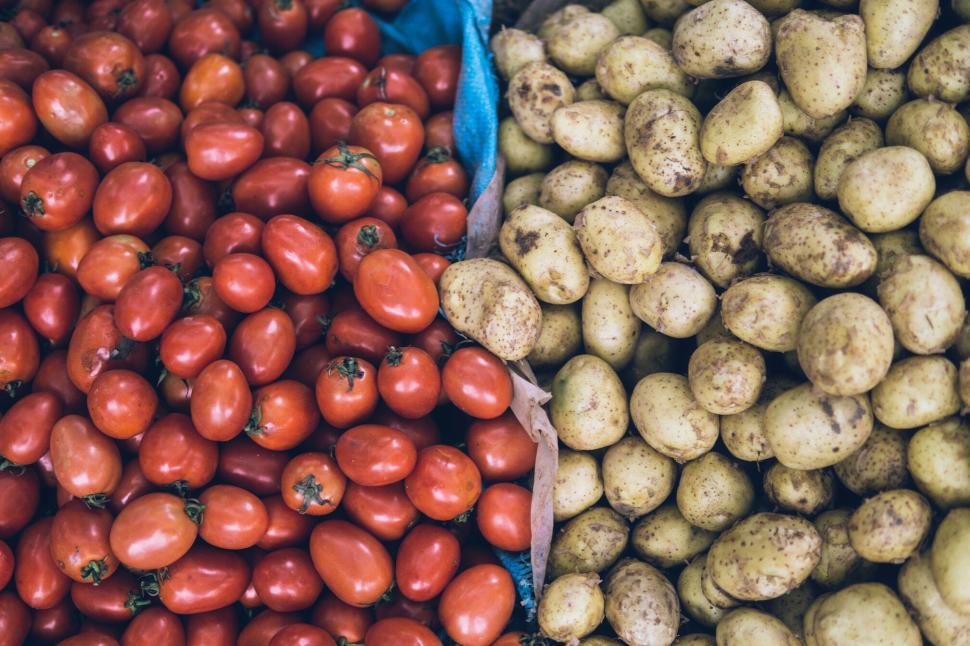 Free Image of Display of vibrant red tomatoes and earthy potatoes at market 