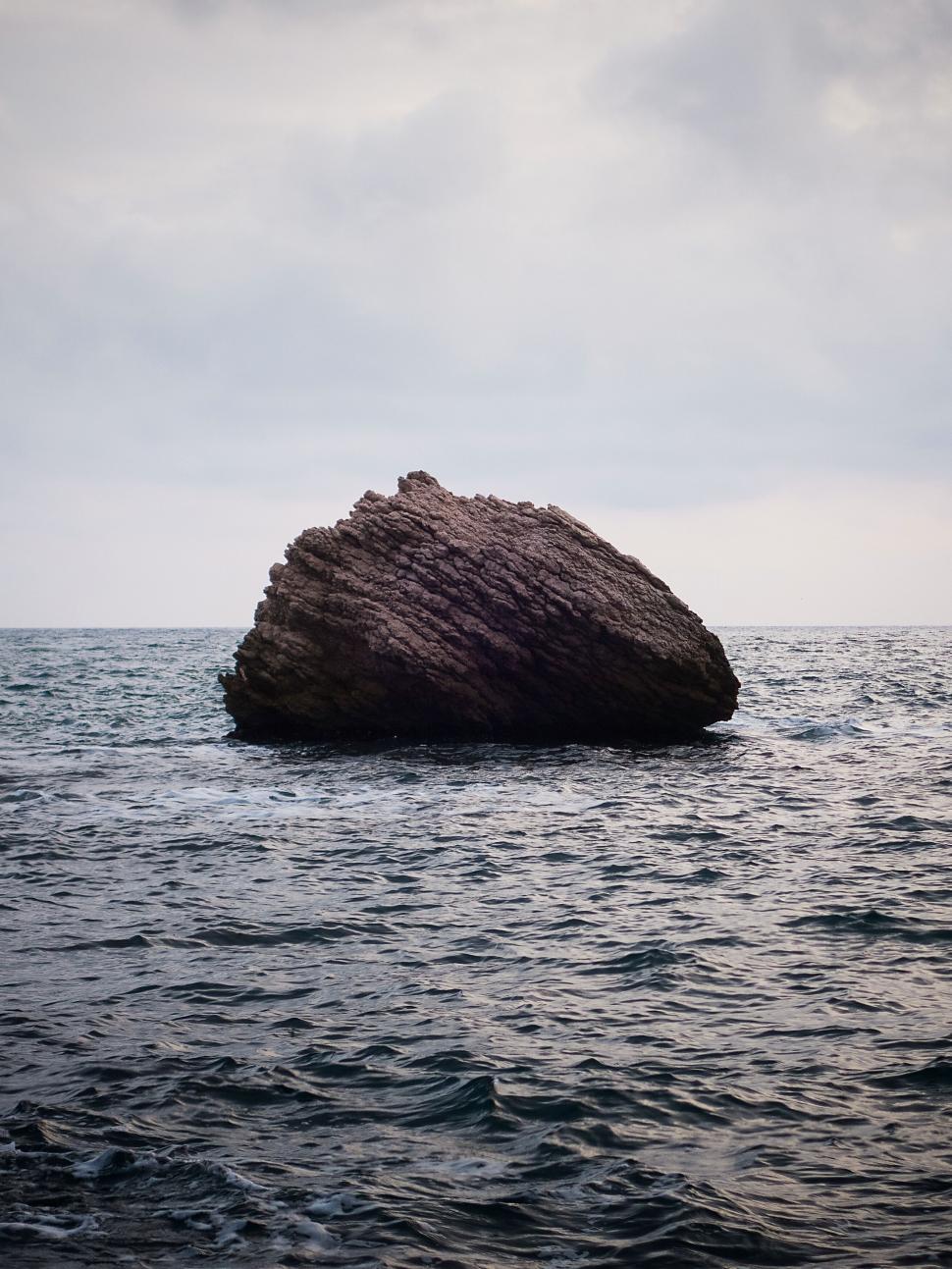 Free Image of Large rock formation standing alone in the middle of the ocean 