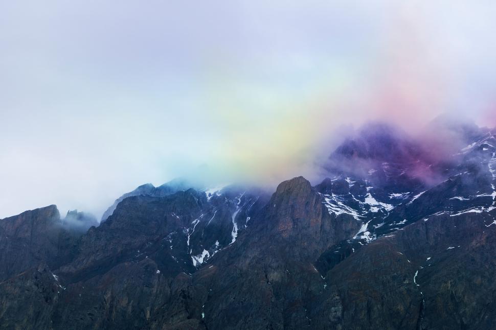 Free Image of Mountain range with multicolored clouds creating a picturesque scene 
