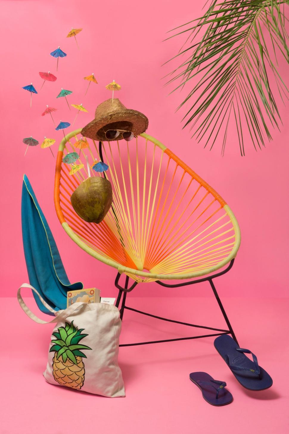 Free Image of Tropical themed still life with chair and vacation accessories 