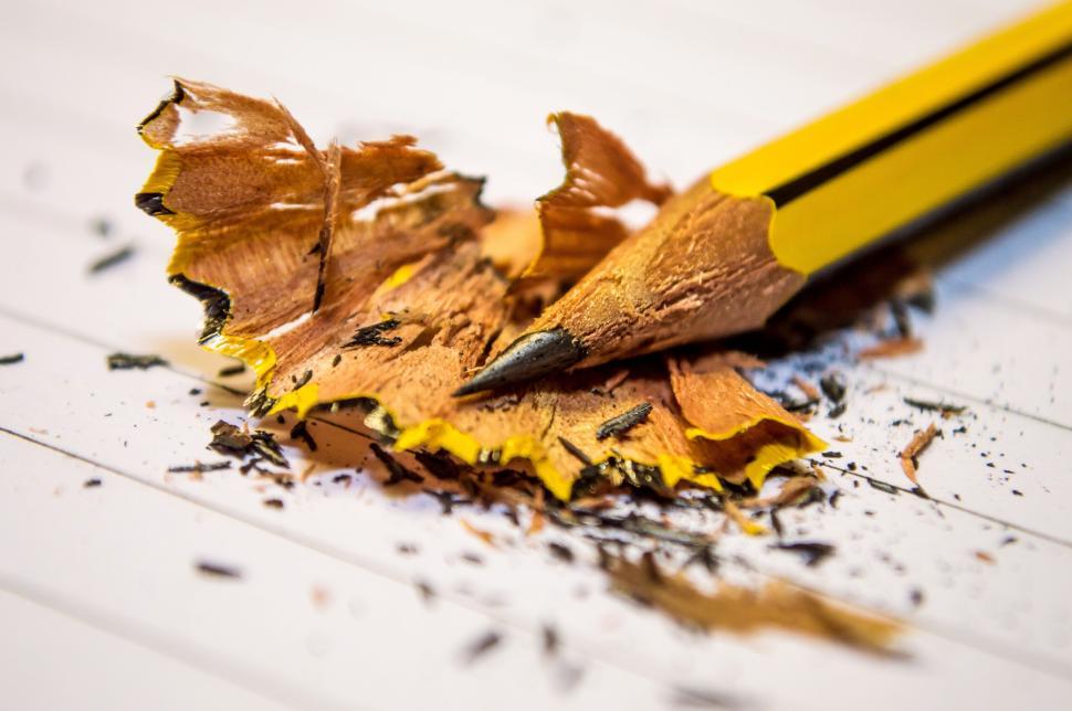 Free Image of Sharpened yellow pencil with shavings on a lined piece of paper. 