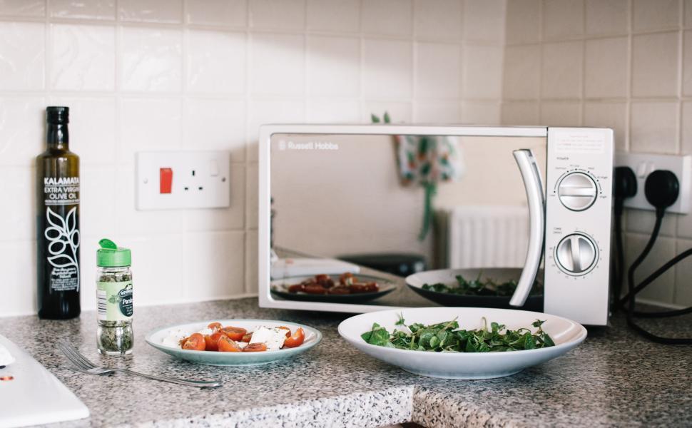 Free Image of Kitchen counter with microwave, salad, olive oil, and herbs 