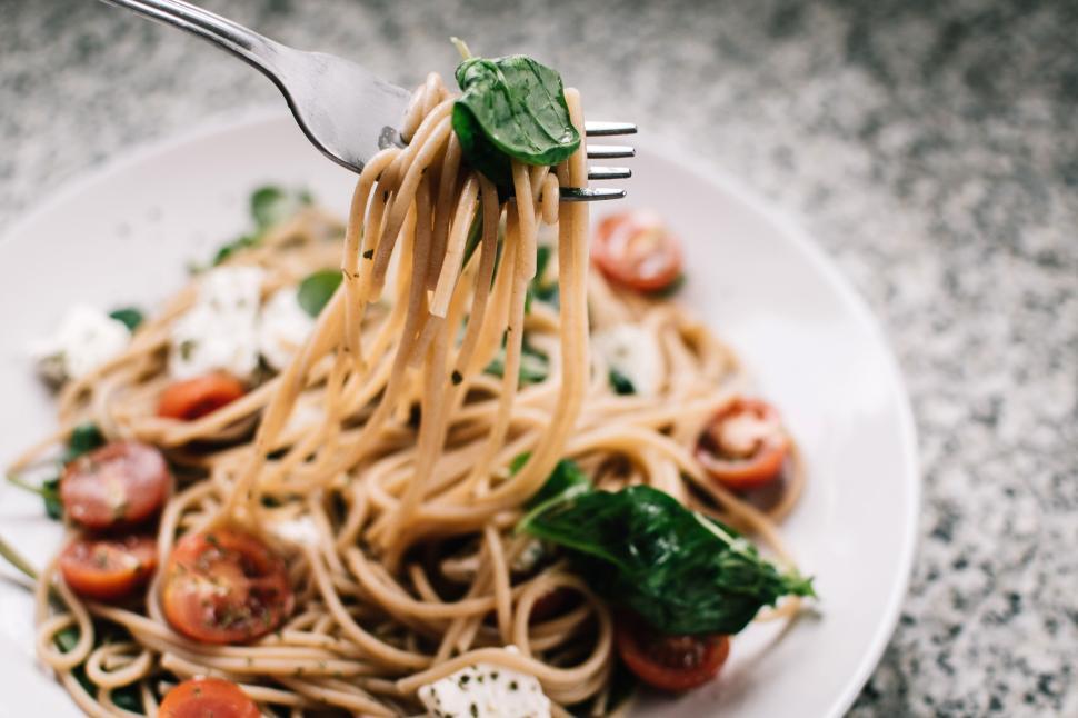 Free Image of Fork lifting pasta with basil and tomatoes in a delicious meal. 