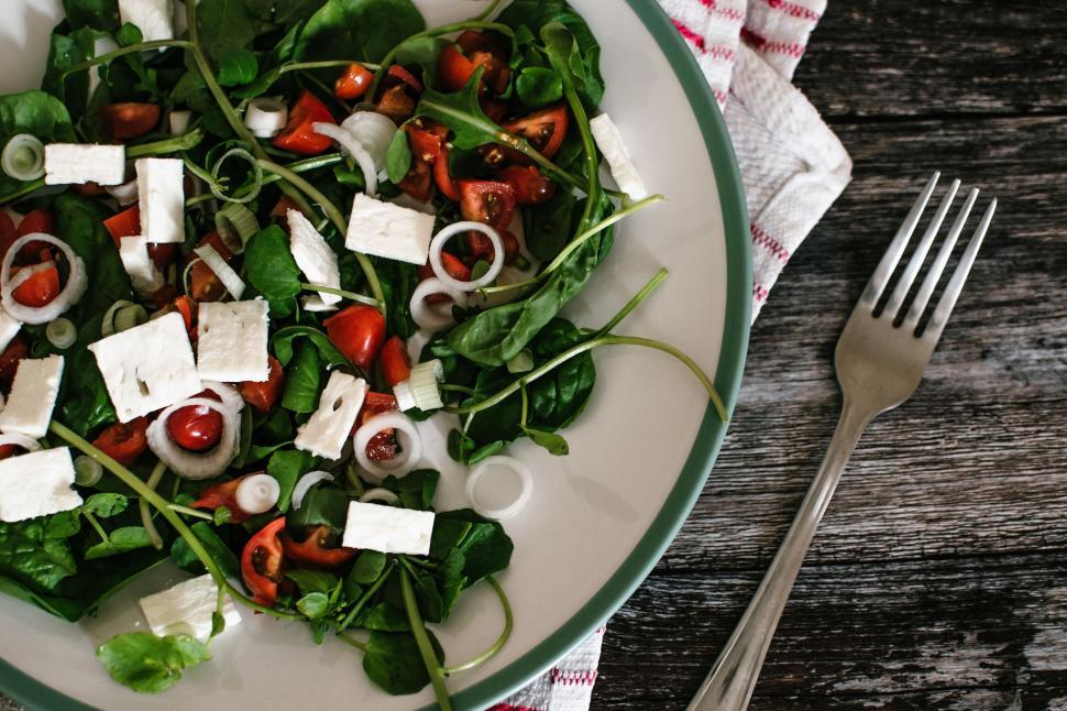 Free Image of A fresh salad with spinach, tomatoes, feta cheese, and onions on plate 