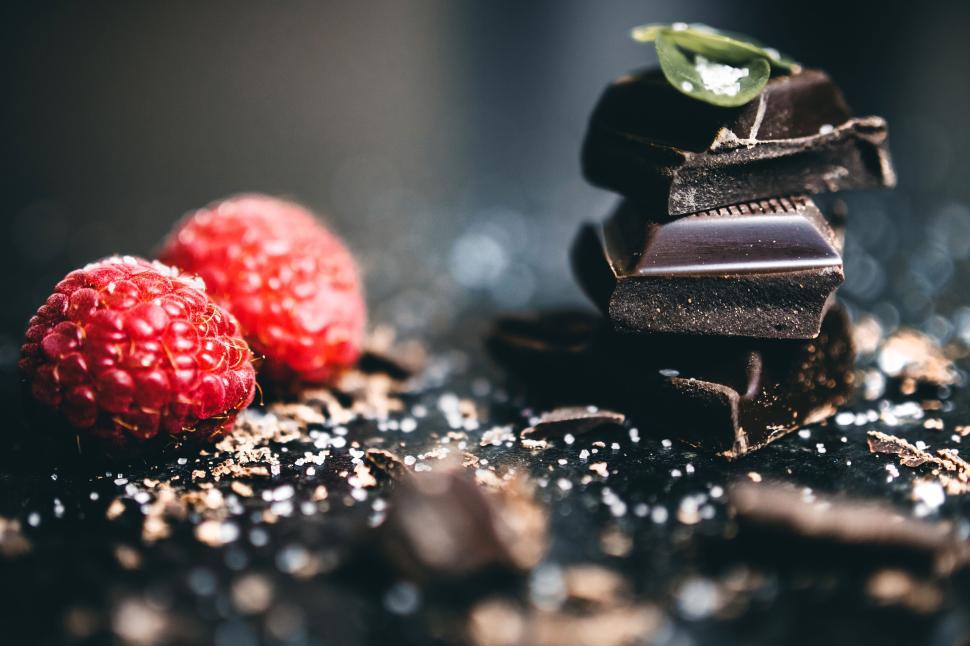 Free Image of Close-up of dark chocolate pieces and raspberries with green leaf. 