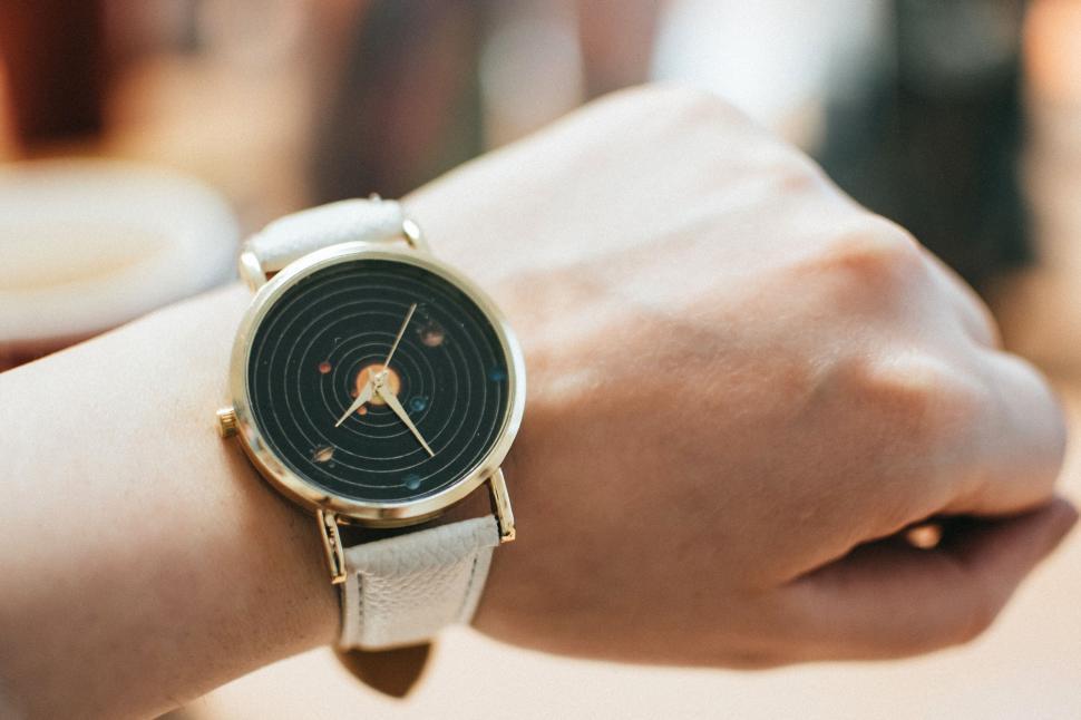 Free Image of Close-up of an elegant wristwatch with planetary design on the wrist. 