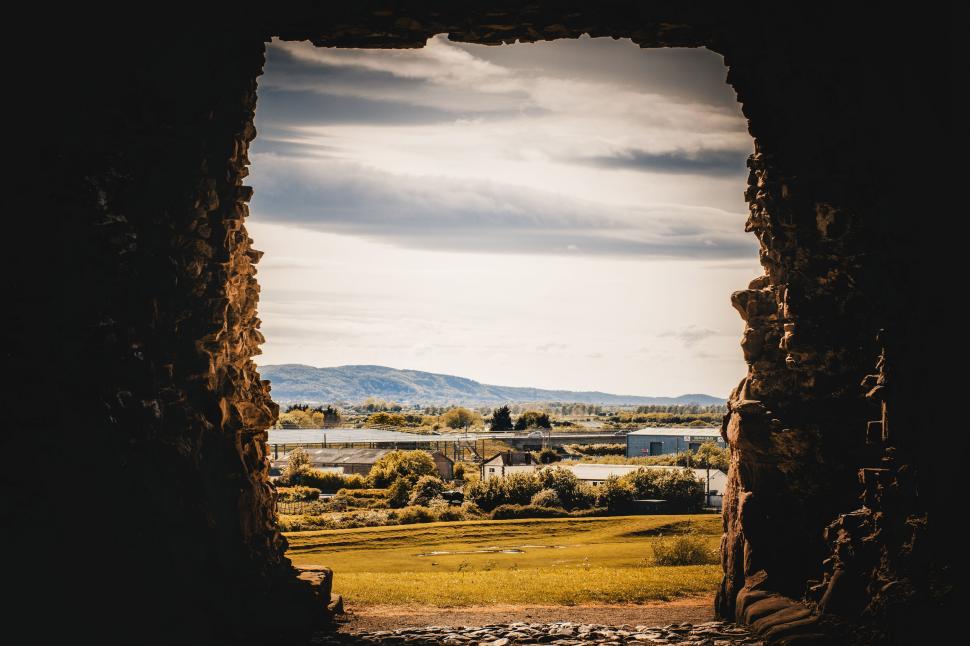 Free Image of Landscape view framed by ancient stone archway, open field beyond. 