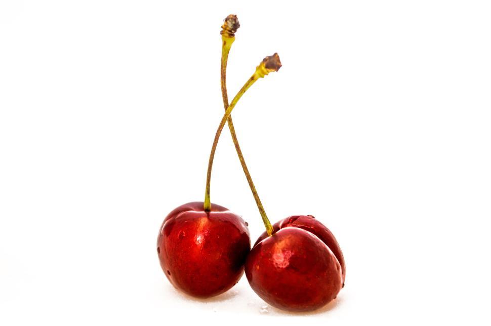 Free Image of Two fresh cherries with stems attached on a white background 
